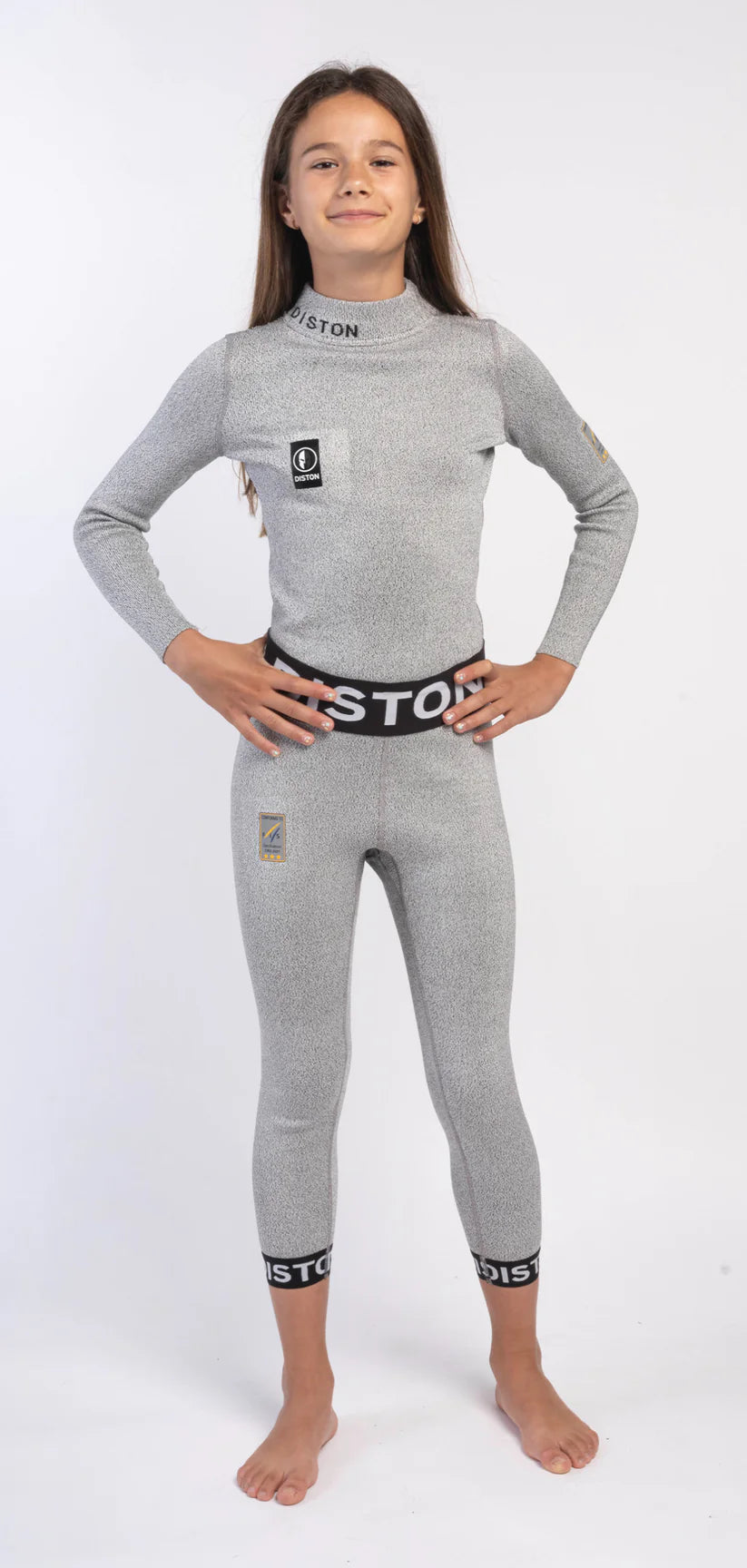 Ein junges Mädchen steht barfuß auf einem weißen Hintergrund und lächelt selbstbewusst in einer Diston DISTON Cut Resistant Unterhose Junior - 4FIS Stars in CRG - CORE / Racing Fit Sportbekleidung mit schwarzem Bund und Bündchen, die Hände auf den Hüften.