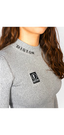 Eine Frau mit langen braunen Haaren trägt das Diston WC Cut Resistant Top Women - 4FIS Stars in CRG - CORE / Racing Fit mit grauem Rippenmuster, gesticktem "DISTON" in der Nähe des Kragens und einem schwarz-weißen rechteckigen Logoaufnäher auf der Brust.