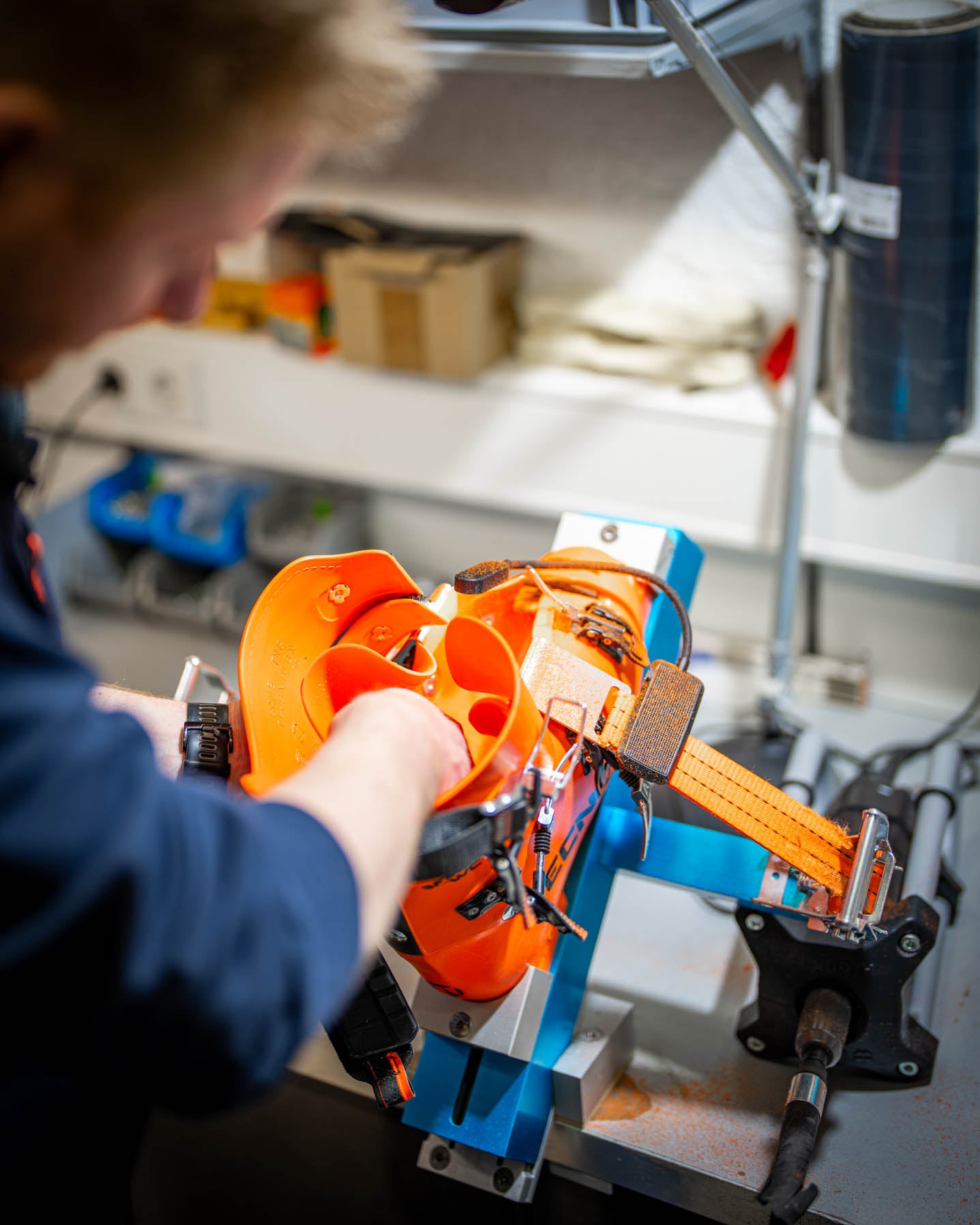 Anpassung der Skischale bei SF Sports: Eine orangefarbene Skischuhschale wird erhitzt, um punktuelle Druckstellen zu reduzieren. Das Bild zeigt, wie die Schale individuell zugeschnitten und mit Fräswerkzeugen bearbeitet wird, um eine perfekte Passform und maximalen Komfort zu gewährleisten.