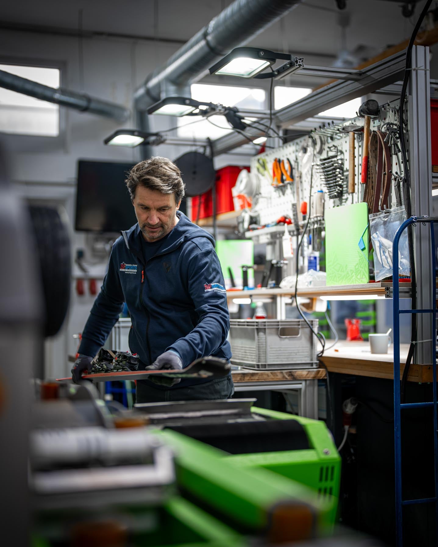 Ein Mitarbeiter bei SF Sports bereitet die Belagsstruktur eines Skis mit einer speziellen Maschine vor. Diese präzise Bearbeitung verbessert die Gleitfähigkeit und Kontrolle.