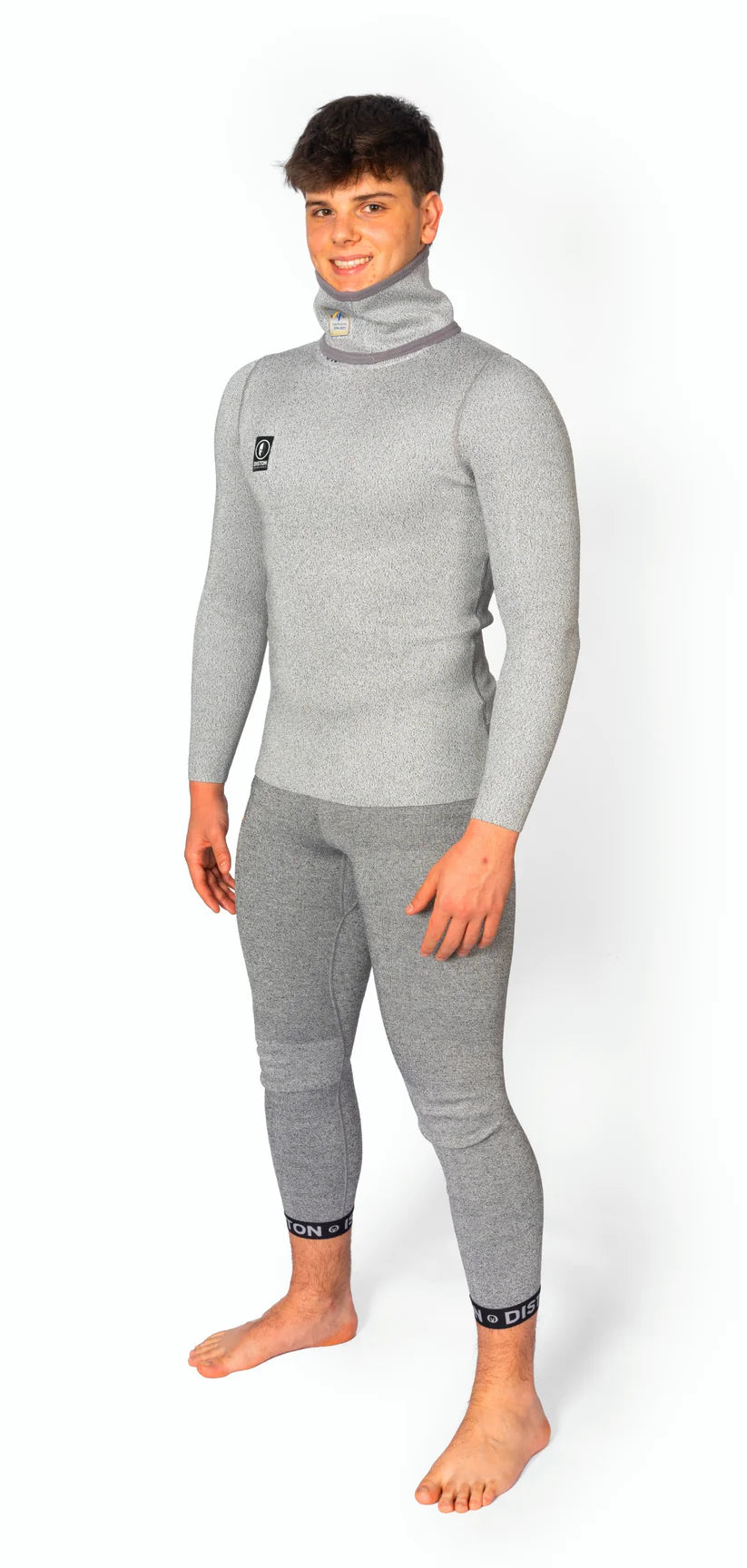 Ein Mann steht barfuß vor einem weißen Hintergrund und lächelt in die Kamera. Er trägt die Diston DISTON WC Cut Resistant Underpants Men - 5FIS Stars in CRG - PRO/Racing Compression Fit, die sowohl Leistung als auch Komfort bietet.