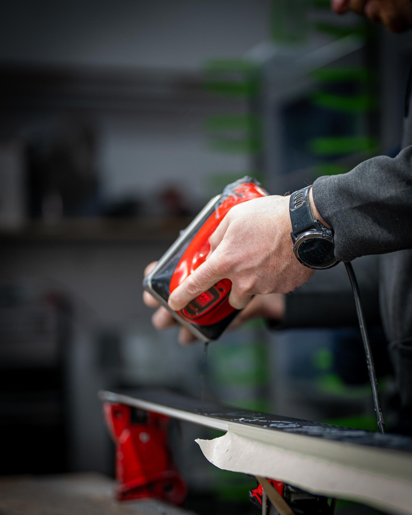 Ein Mitarbeiter schmilzt Wachs mit einem Bügeleisen und trägt es sorgfältig per Hand auf den Ski auf. Dieser Prozess gewährleistet maximale Qualität und Anpassung an die spezifischen Rennbedingungen.