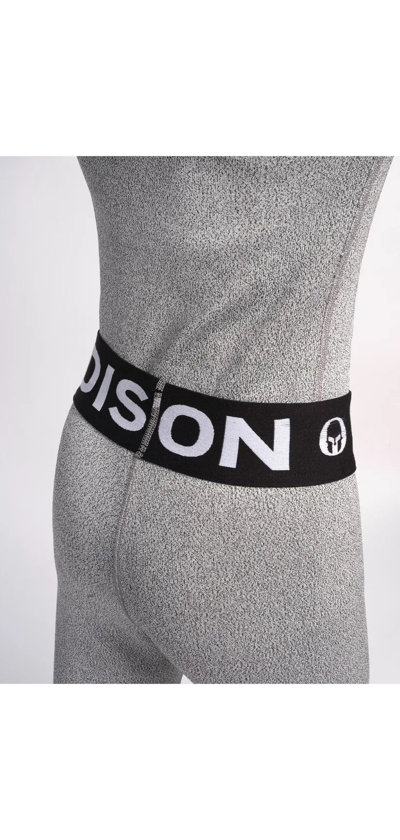 Nahaufnahme einer Person, die Diston Cut Resistant Underpants Junior trägt - hellgraue, strukturierte Sportleggings mit schwarzem Bund und auffälligem weißem "DISTON"-Schriftzug und Logo. Ideal für Skirennläufer. Einfarbig weißer Hintergrund.