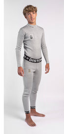 Ein Jugendlicher mit hellbraunem Haar steht barfuß und lächelt in die Kamera. Er trägt ein passgenaues Diston WC Schnittfeste Hosen Herren - 4FIS Stars in CRG - CORE / Racing Fit Set: ein hellgraues langärmeliges Oberteil und eine passende schnittfeste Unterhose mit Diston-Branding.