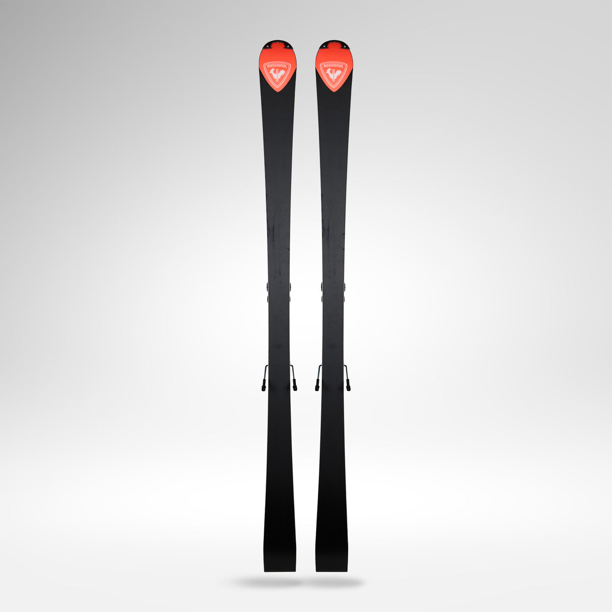 Ein Paar Rossignol HERO FIS SL FAC 165 R22 2026/2027 von Rossignol mit roten Akzenten und weißem Logo im Spitzenbereich steht aufrecht vor einem schlichten, hellgrauen Hintergrund.