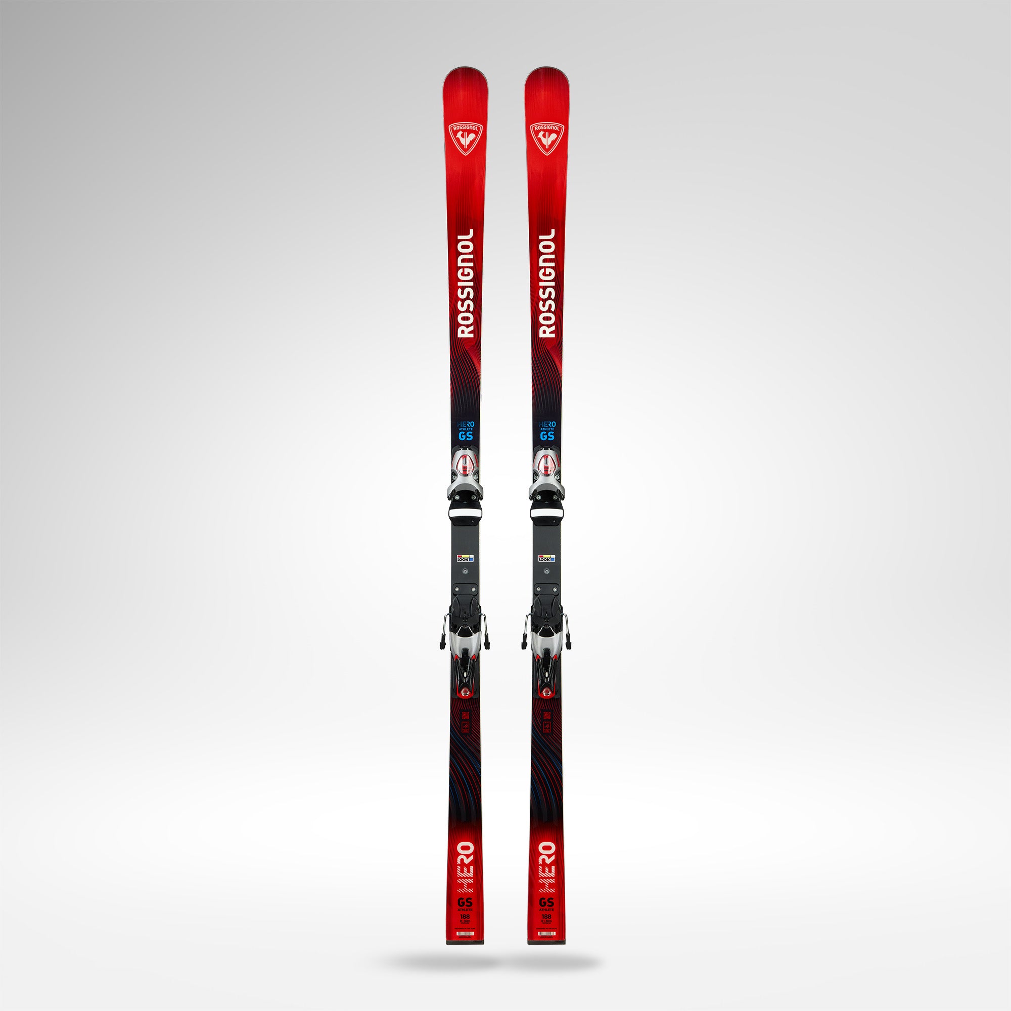 Ein Paar Rossignol HERO ATHLETE GS 185 R22 2026/2027 mit schwarzer Bindung steht aufrecht auf einem hellgrauen Hintergrund, mit weißem Branding und einem rot-schwarzen Farbverlauf. Ideal für Riesenslalom Rennski Veranstaltungen.