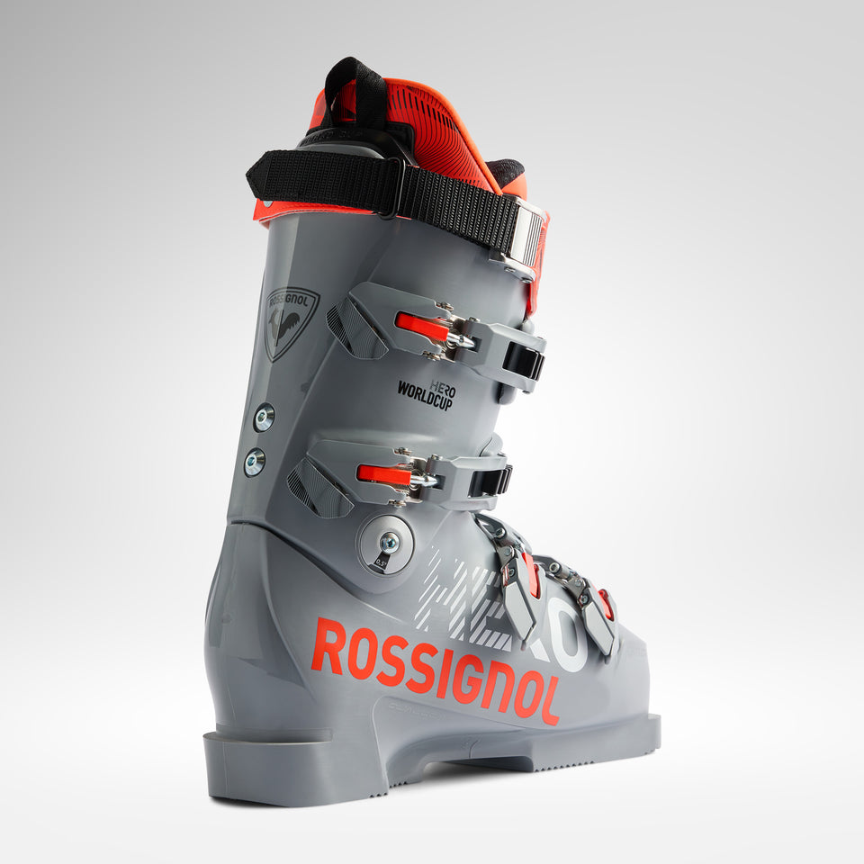 Der Rossignol HERO WORLD CUP ZC - POWER GREY 2026/2027 hat ein graues und rotes Design mit drei Metallschnallen, einem oberen schwarzen Riemen und einem auffälligen orangefarbenen ROSSIGNOL-Branding an der Seite, das für World Cup Race Fit vor einem hellen Hintergrund gemacht ist.