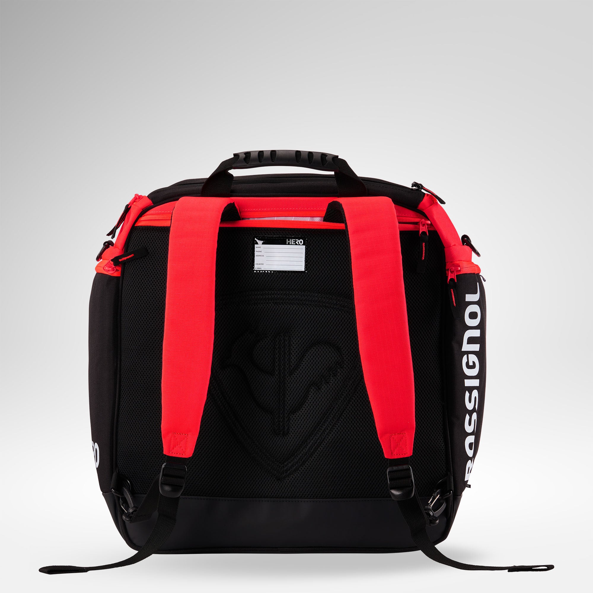 Der Rossignol HERO HEATED BAG 230V ist ein schwarz-roter Rucksack mit Rossignol-Logo, zwei Schulterriemen, einem Tragegriff oben und einem sichtbaren Namensschildhalter. Er ist im Stil einer Skischuhtasche gestaltet und auf einem hellgrauen Hintergrund abgebildet.