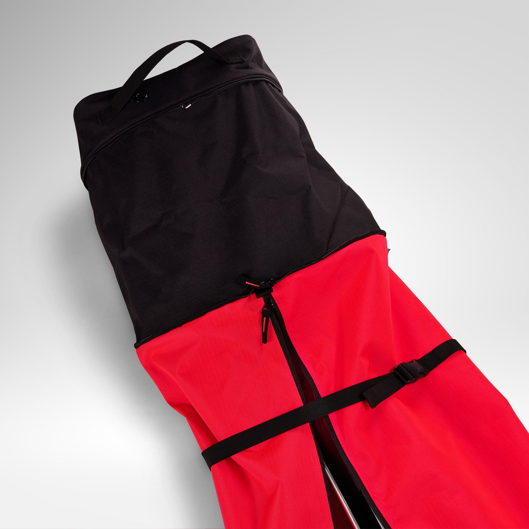Eine rot-schwarze Rossignol HERO SKI BAG 2/3P ADJUSTABLE 190/220 mit Reißverschluss und Tragegriff, teilweise geöffnet, ist vor einem hellgrauen Hintergrund abgebildet. Diese wasserdichte Skitasche von Rossignol ist für 2–3 Paar Ski ausgelegt und bietet zuverlässigen Schutz und Komfort für Ihre Winterabenteuer.