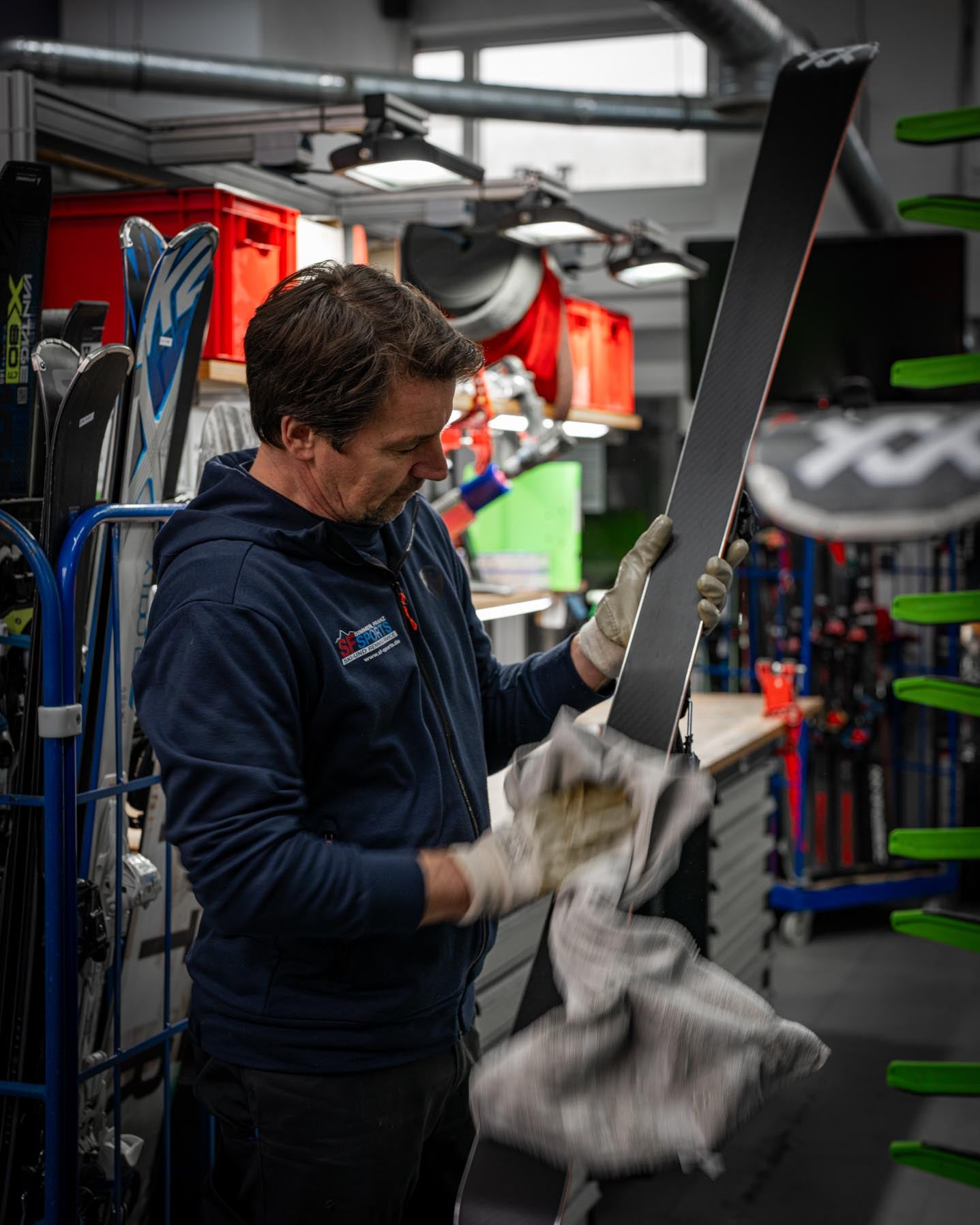 Ein Mitarbeiter bei SF Sports bereitet einen Ski für den Rennservice vor. Der Ski erhält einen präzisen Kantenschliff, eine individuelle Belagsstruktur und die passende Wachsschicht, um den Anforderungen für verschiedene Disziplinen gerecht zu werden.
