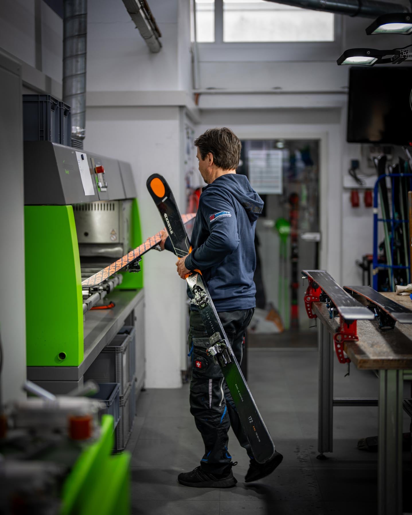 Ein Mitarbeiter legt einen Ski in die Maschine, um den Belag für den Rennservice mit einem Strukturschliff zu versehen. Die Abstimmung erfolgt exakt auf Schnee- und Wetterverhältnisse, um den Luft- und Schneewiderstand zu minimieren.