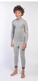 Ein lächelnder Junge mit lockigem Haar steht barfuß vor einem weißen Hintergrund und trägt das Diston DISTON Cut Resistant Top Junior - 3FIS Stars in CRG - BASE / Performance Fit-perfekt für aufstrebende Skirennläufer.
