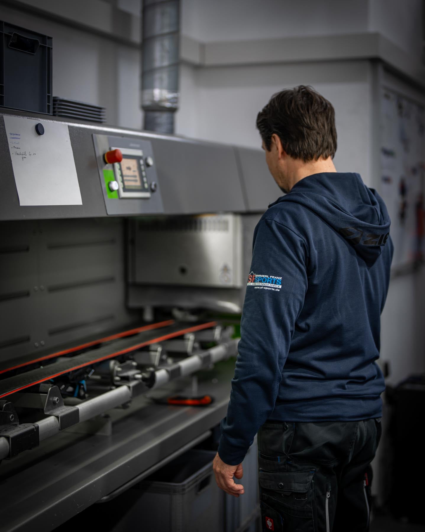 Die Wintersteiger Basejet Maschine, die für schnelle und effektive Reparaturen von Ski- und Snowboardbelägen bei SF Sports verwendet wird. Davor ist ein Mitarbeiter zu sehen, der die Maschine bedient.