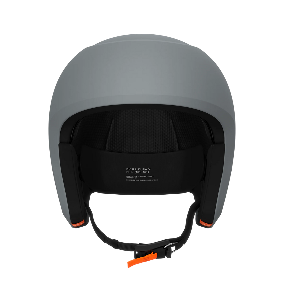Ein mattgrauer POC Sports Poc Skull Dura X Mips Helm von hinten gesehen, mit sichtbarer Innenpolsterung, einem schwarzen Kinnriemen mit orangefarbenen Laschen und weißem Text auf der Innenseite.