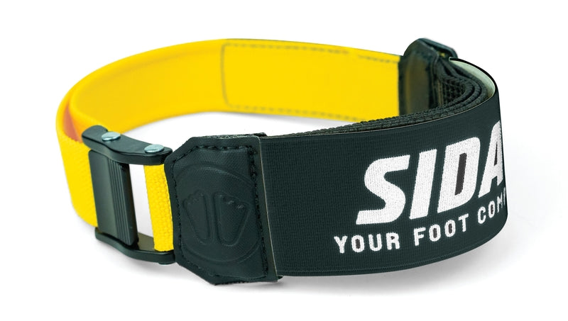 Der Sidas Sidas Powerstrap P3 ist ein gelb-schwarzes, verstellbares Skischuh-Accessoire mit einem elastischen Strap für optimale Skischuh-Kontrolle und dem Aufdruck "YOUR FOOT COM" in weiß auf dem schwarzen Teil.