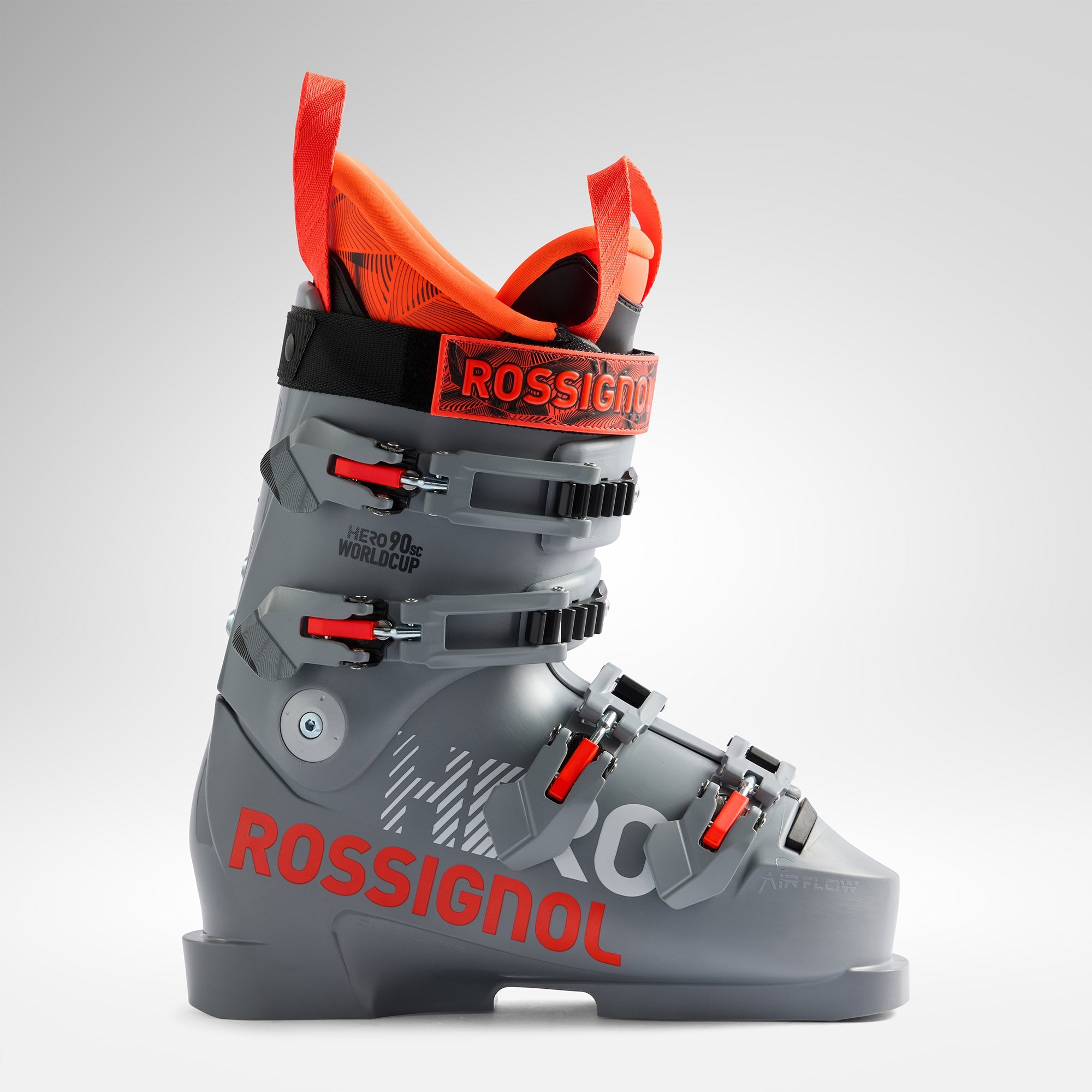 Ein grauer und orangefarbener Rossignol-Skischuh mit schwarzer und roter Schnalle, mit der Aufschrift "HERO 90 WC" und "ROSSIGNOL" an der Seite, abgebildet auf einem schlichten hellen Hintergrund.