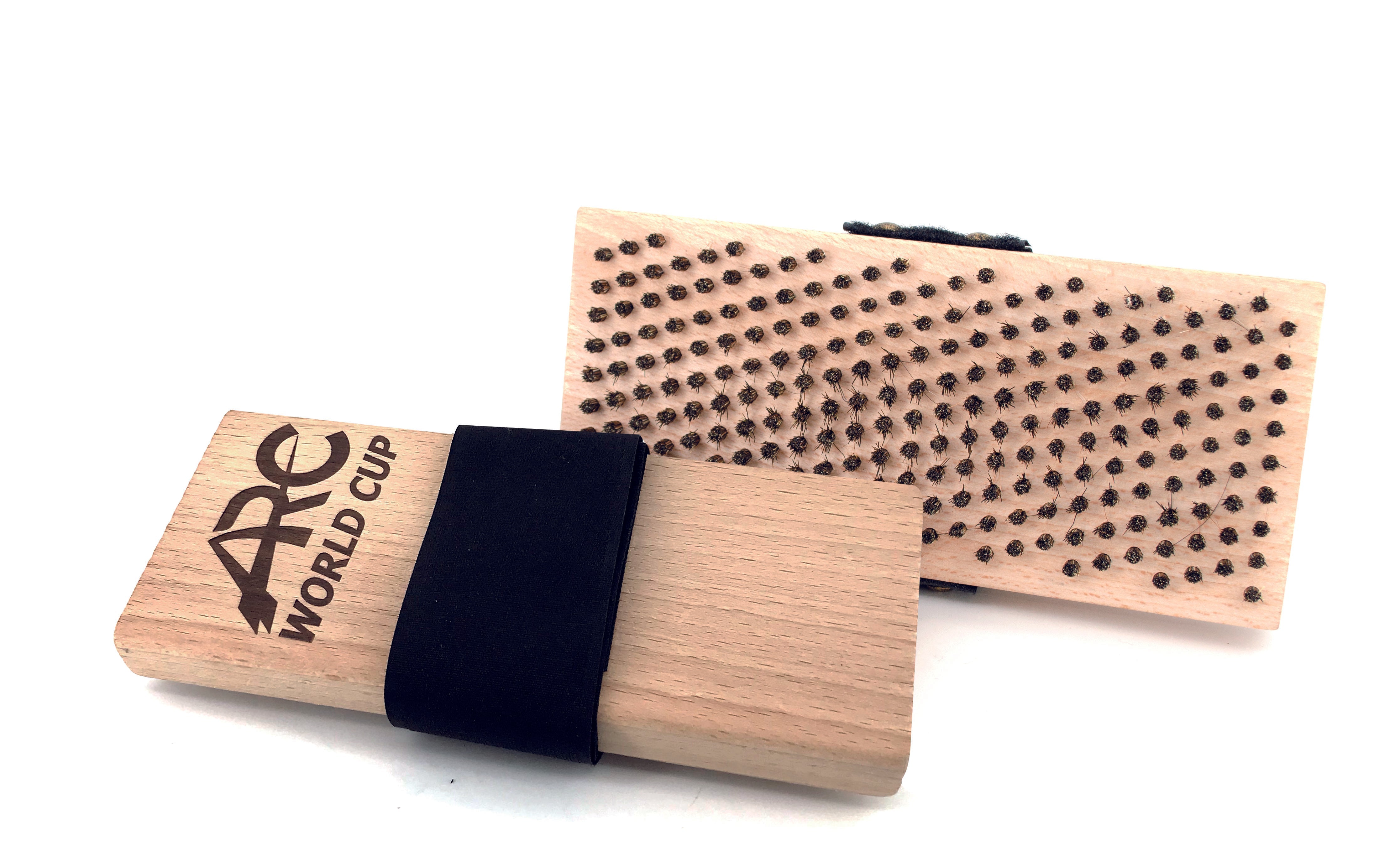 Zwei rechteckige Holzbürsten mit schwarzen Riemen, eine mit der Bürstenseite mit Metallborsten und die andere mit dem eingravierten ARC WORLD CUP Logo. Beide haben eine einfache, natürliche Holzoberfläche.