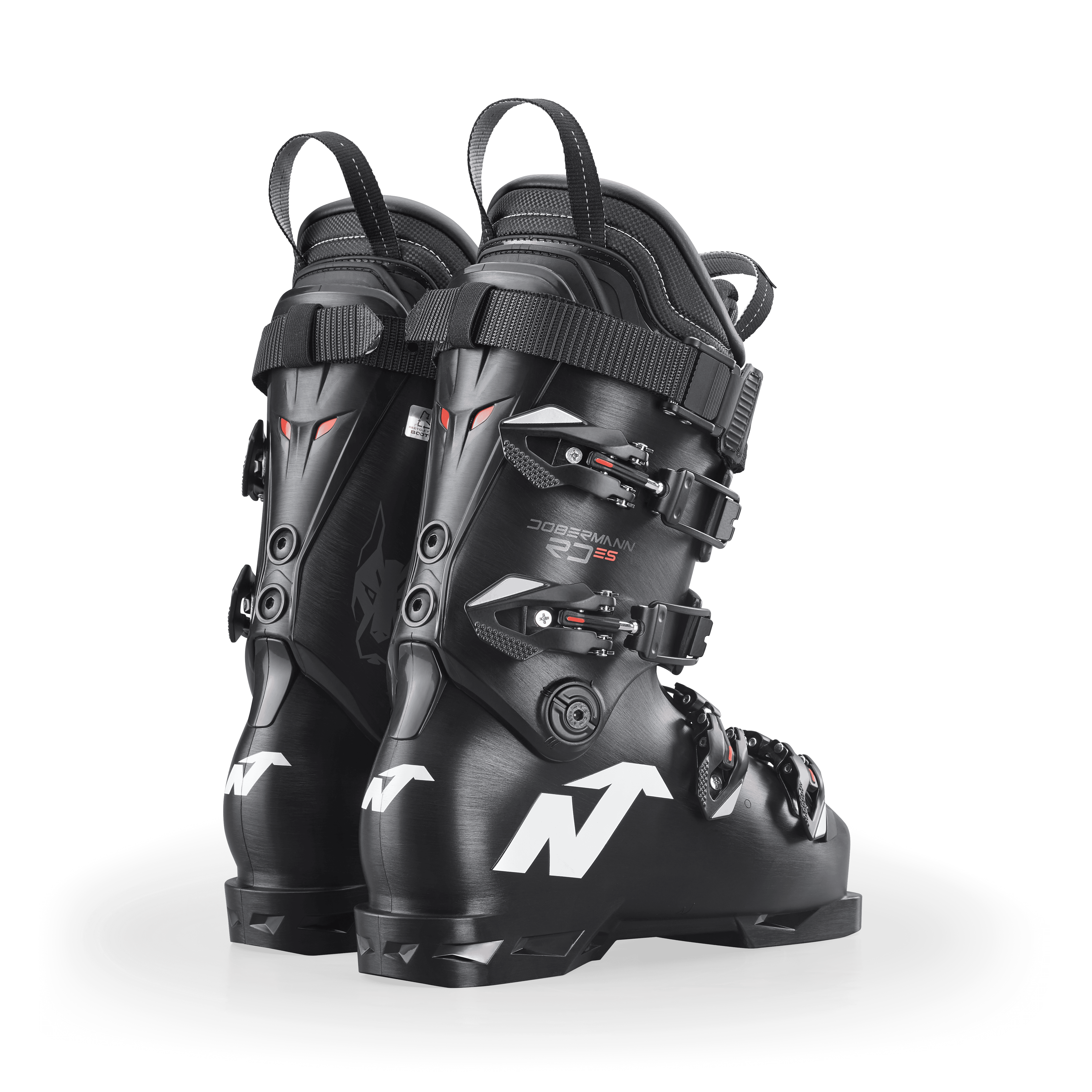 Ein Paar schwarze Nordica DOBERMANN 5 RD-93 EXTRA STIFF 2026/2027 Skischuhe mit silbernen Schnallen und weißem Branding stehen Rücken an Rücken auf einem hellen Hintergrund.