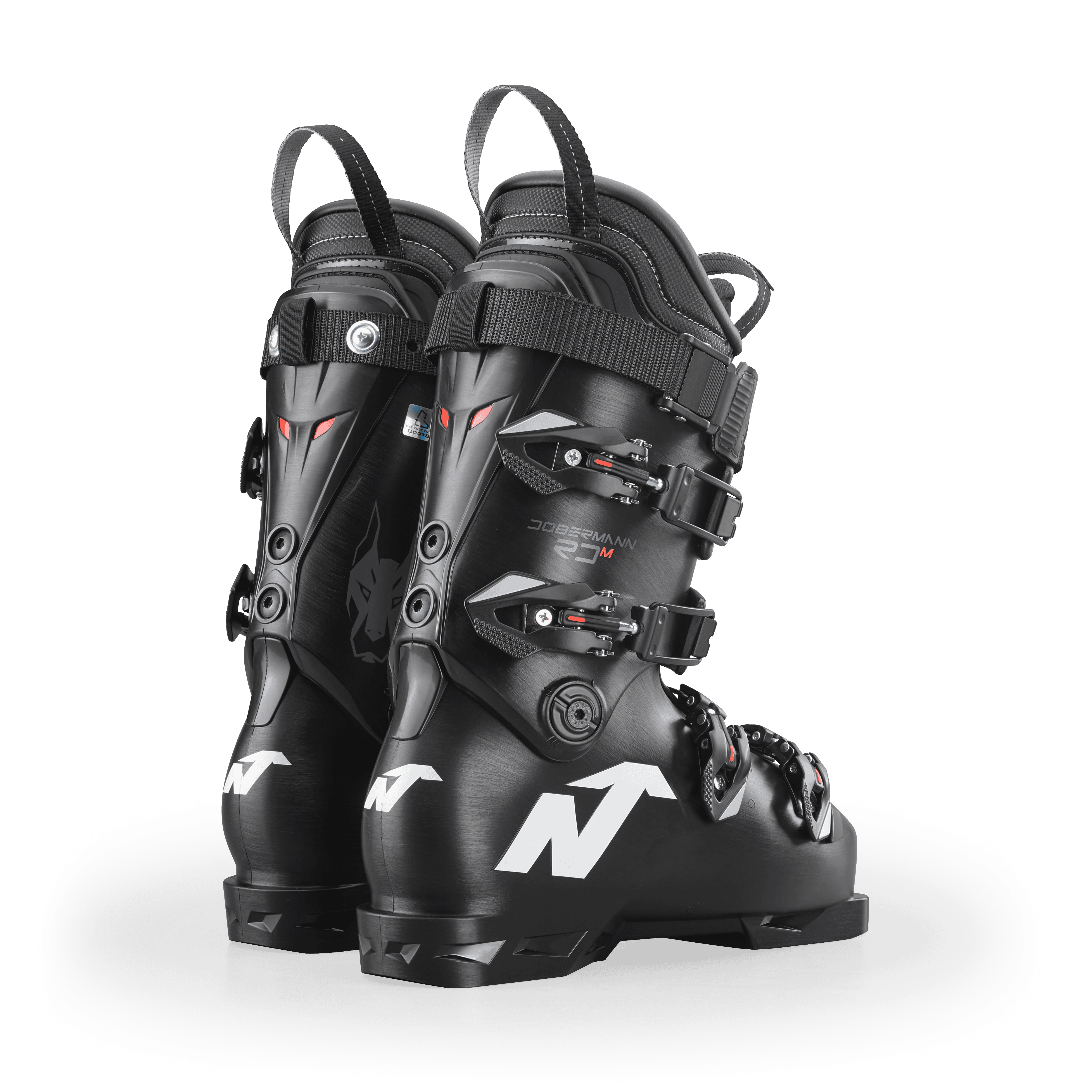 Ein Paar schwarze Nordica DOBERMANN 5 RD-93 MEDIUM 2026/2027 Skischuhe mit silbernen Schnallen und weißen N-Logos, von hinten auf weißem Hintergrund.