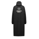 Der Head Rain Coat Junior schwarz 2026/2027 von Head ist ein langer, schwarzer Regenmantel mit Kapuze, weißem Totenkopf und gekreuzten Skiern sowie dem Schriftzug WORLD CUP REBELS" auf dem Rücken.