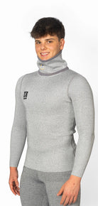 Ein junger Mann trägt das Diston DISTON WC Cut Resistant Top Men - 4FIS Stars in CRG - CORE / Racing Fit, hellgrau, und die dazu passende Hose, steht vor einem schlichten weißen Hintergrund und lächelt in die Kamera.