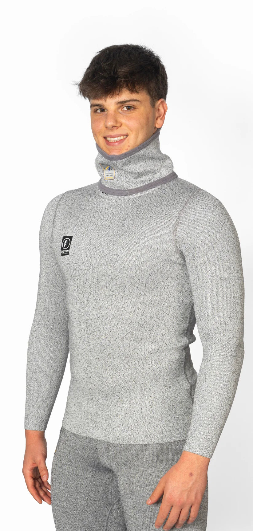 Ein junger Mann trägt das Diston DISTON WC Cut Resistant Top Men - 4FIS Stars in CRG - CORE / Racing Fit, hellgrau, und die dazu passende Hose, steht vor einem schlichten weißen Hintergrund und lächelt in die Kamera.