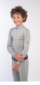Ein Junge mit lockigem braunem Haar lächelt in die Kamera. Er trägt eine Diston DISTON Cut Resistant Unterhose Junior - 4FIS Stars in CRG - CORE / Racing Fit und steht vor einem schlichten weißen Hintergrund.