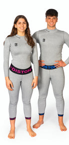Ein Mann und eine Frau in passenden hellgrauen, taillierten Diston-Outfits mit rosa und blauen DISTON-Bünden lächeln vor einem weißen Hintergrund und präsentieren die DISTON WC Cut Resistant Unterhose Women - 4FIS Stars in CRG - CORE / Racing Fit.