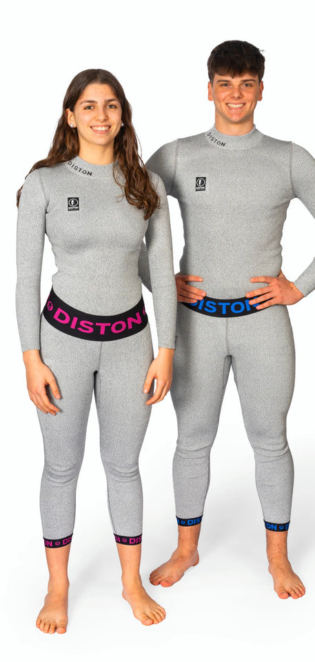 Ein Mann und eine Frau in passenden hellgrauen, taillierten Diston-Outfits mit rosa und blauen DISTON-Bünden lächeln vor einem weißen Hintergrund und präsentieren die DISTON WC Cut Resistant Unterhose Women - 4FIS Stars in CRG - CORE / Racing Fit.