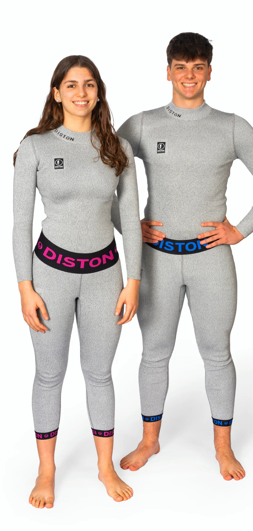 Ein Mann und eine Frau in passenden hellgrauen, taillierten Diston-Outfits mit rosa und blauen DISTON-Bünden lächeln vor einem weißen Hintergrund und präsentieren die DISTON WC Cut Resistant Unterhose Women - 4FIS Stars in CRG - CORE / Racing Fit.