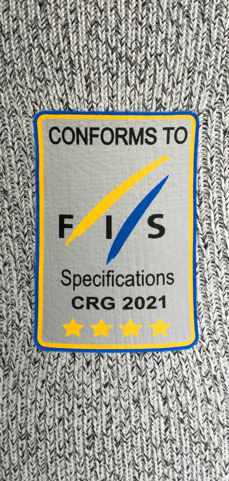Ein Diston-Stoffaufnäher für das DISTON WC Cut Resistant Top Men - 4FIS Stars in CRG - CORE / Racing Fit zeigt "CONFORMS TO FIS Specifications CRG 2021" über fünf gelben Sternen mit blau/gelben Rauten auf grauem Grund - perfekt für Skirennfahrer.