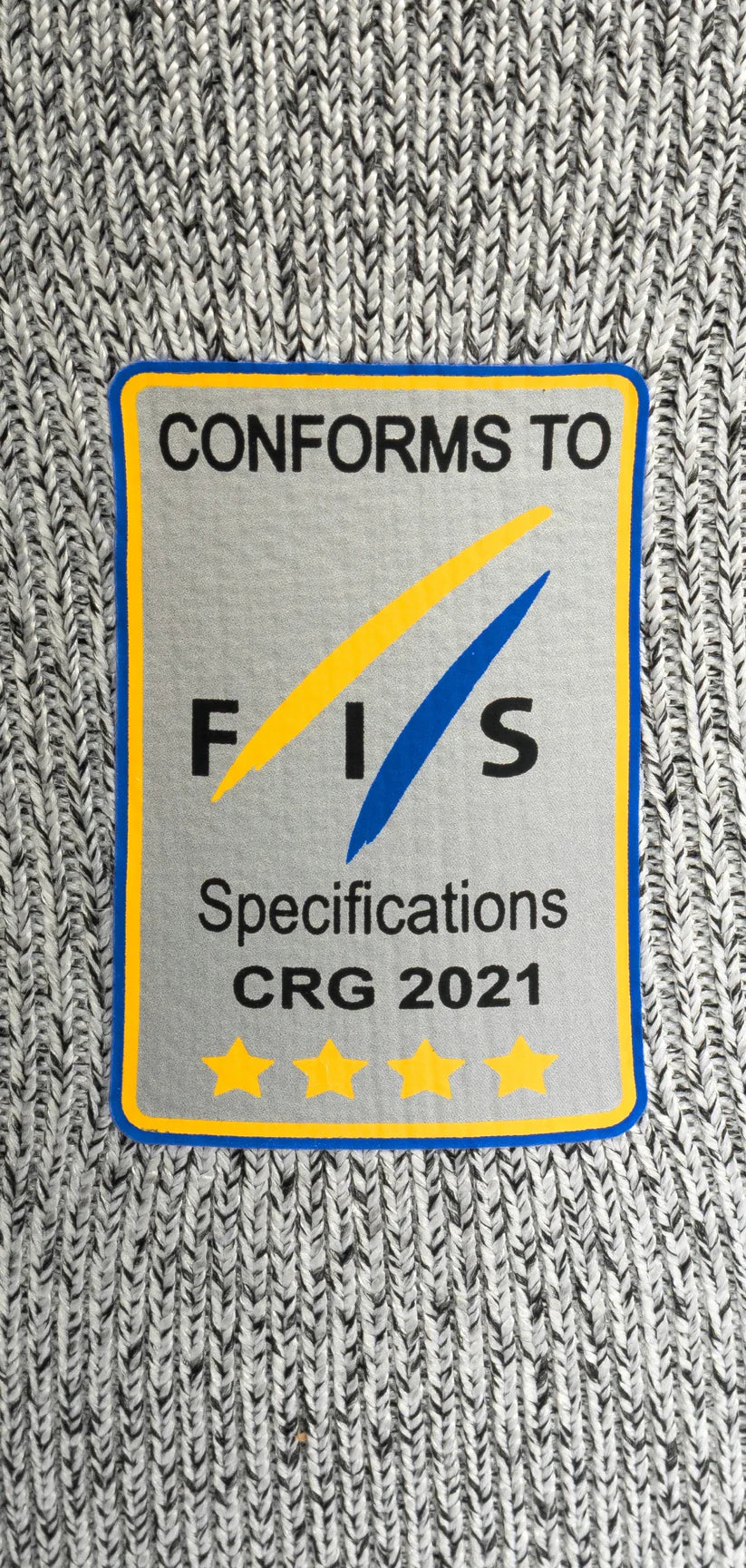 Ein Diston-Stoffaufnäher für das DISTON WC Cut Resistant Top Men - 4FIS Stars in CRG - CORE / Racing Fit zeigt "CONFORMS TO FIS Specifications CRG 2021" über fünf gelben Sternen mit blau/gelben Rauten auf grauem Grund - perfekt für Skirennfahrer.