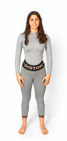 Eine Frau mit langen braunen Haaren steht barfuß, blickt nach vorne und trägt eine Diston WC Cut Resistant Unterhose für Frauen in hellgrauem PRO/Racing Compression Fit mit schwarzen Bund- und Knöchelbändern mit der Aufschrift DISTON.