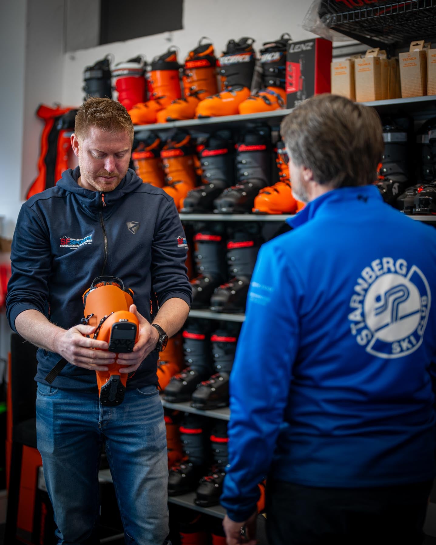 Ein Kunde bei der Bootfitting-Beratung bei SF Sports. Der passende Skischuh wird individuell ausgewählt, während im Hintergrund eine breite Auswahl an Skischuhen zu sehen ist. Diese maßgeschneiderte Beratung garantiert Komfort und optimale Leistung auf der Piste.