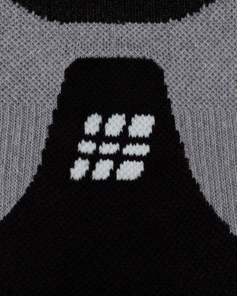 Nahaufnahme der CEP Ski Ultralight Socken 3.0 in Schwarz/Grau für Damen, mit einem Strickmuster auf schwarzem Hintergrund und einem Motiv aus sechs weißen Punkten in zwei Reihen, umgeben von einem grauen Bereich.