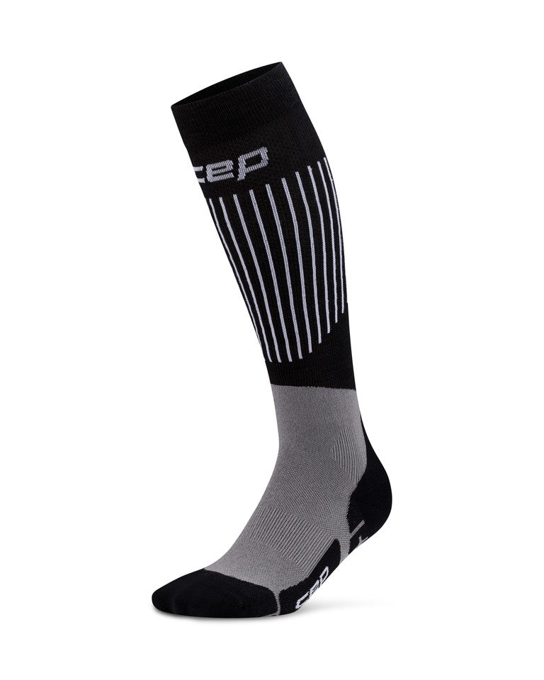 Eine einzelne ultraleichte CEP-Skisocke 3.0 für Damen in Schwarz und Grau mit weißen vertikalen Streifen und CEP-Logo am Schaft und an der Fußsohle.