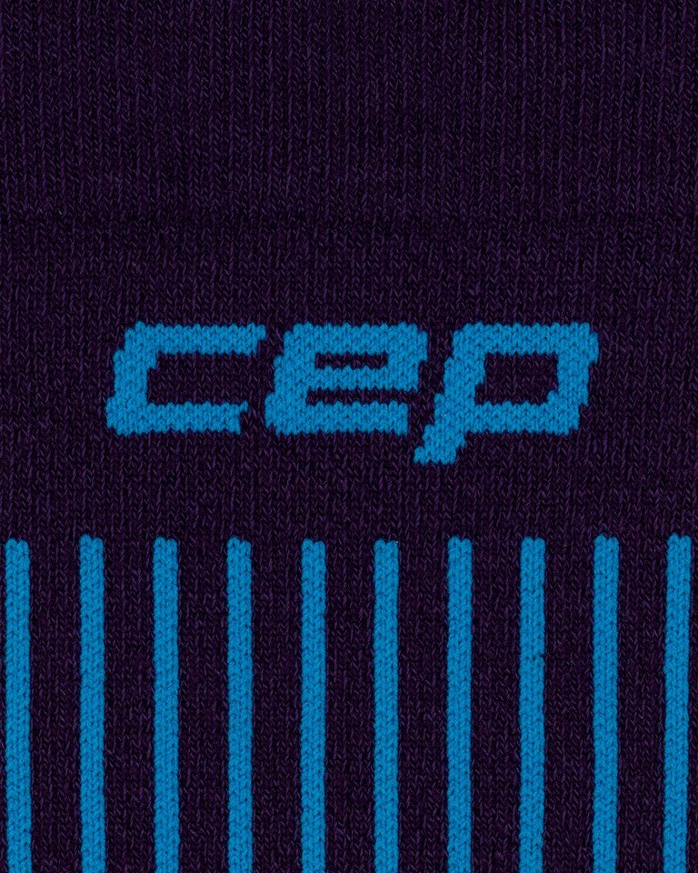 Nahaufnahme der dunkelvioletten und blauen CEP Ski Ultralight Socken 3.0 für Herren, auf denen der Markenname „CEP“ in hellblauer Schrift über mehreren vertikalen blauen Linien zu sehen ist.