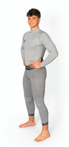 Ein junger Mann steht barfuß auf einem weißen Hintergrund, lächelnd und mit den Händen in den Hüften. Er trägt die DISTON WC Cut Resistant Unterhose Men - 5FIS Stars in CRG - PRO/Racing Compression Fit von Diston in Hellgrau.