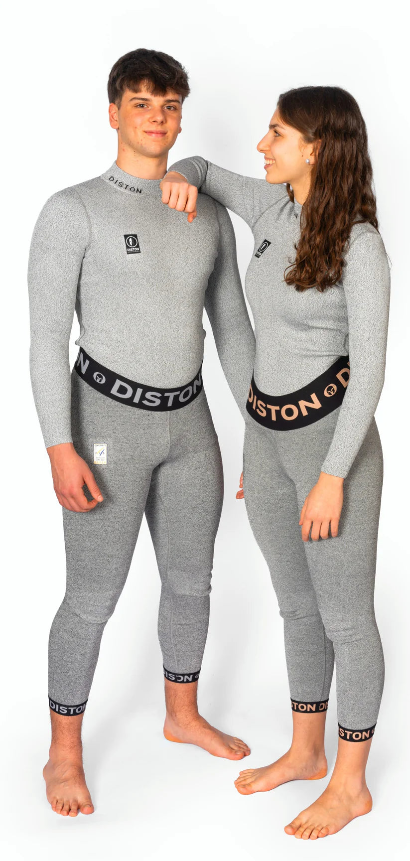 Ein junger Mann und eine junge Frau stehen nebeneinander, beide in passenden Diston WC Cut Resistant Unterhosen Men - 5FIS Stars in CRG - PRO/Racing Compression Fit, mit DISTON Branding an Bund und Bündchen. Die Frau lächelt und stützt ihren Arm auf seine Schulter.