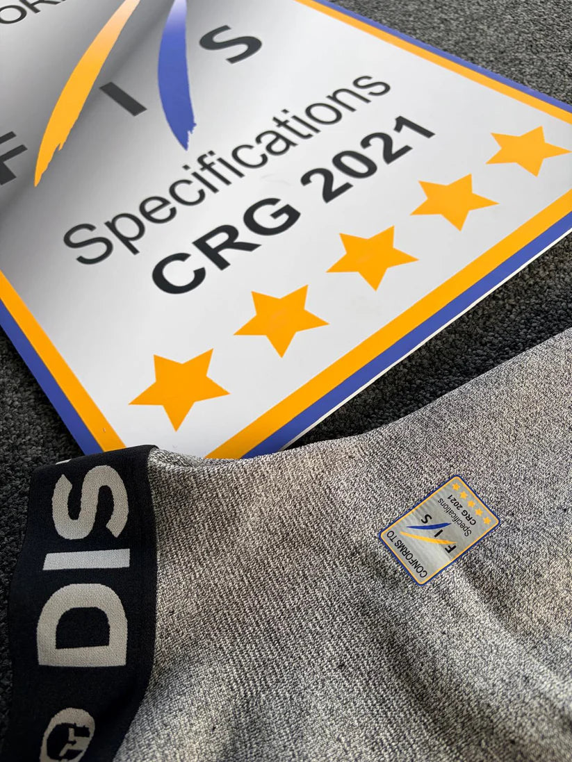 Nahaufnahme einer Diston DISTON WC Cut Resistant Unterhose Men - 5FIS Stars in CRG - PRO/ Racing Compression Fit, die auf einer strukturierten grauen Fläche neben einem FIS Certified S CALENDAR Zeichen liegt.