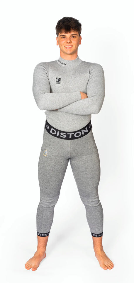 Ein junger Mann steht barfuß, lächelnd und mit verschränkten Armen in einer Diston WC Cut Resistant Unterhose Men - 5FIS Stars in CRG - PRO/Racing Compression Fit vor einem schlichten weißen Hintergrund.