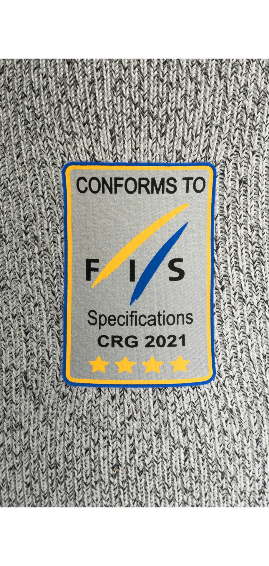 Die grau gestrickte Diston DISTON WC Schnittfeste Hosen Herren hat einen rechteckigen Aufnäher mit der Aufschrift "CONFORMS TO FIS Specifications CRG 2021" und vier goldenen Sternen, die blau und gelb umrandet sind - ein Qualitätsmerkmal für Skirennsport-Unterwäsche.