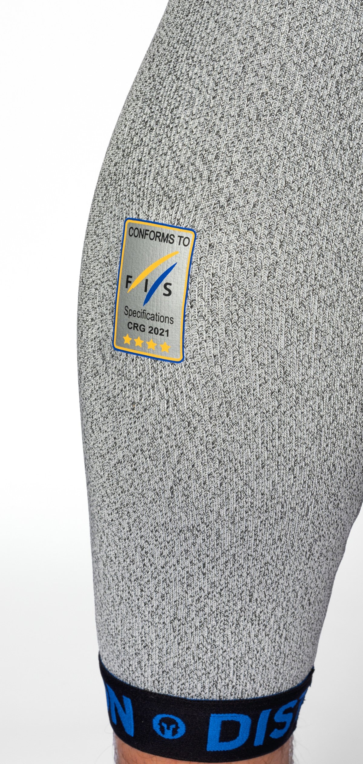 Nahaufnahme des Oberschenkels einer Person, die die grau strukturierten DISTON WC Schnittfeste Hosen Herren - 4FIS Stars in CRG - CORE / Racing Fit von Diston trägt, mit einem schwarz-blauen Bund und einem blau-gelben Etikett mit der Aufschrift Conforms to FIS Specifications, mit vier Sternen.