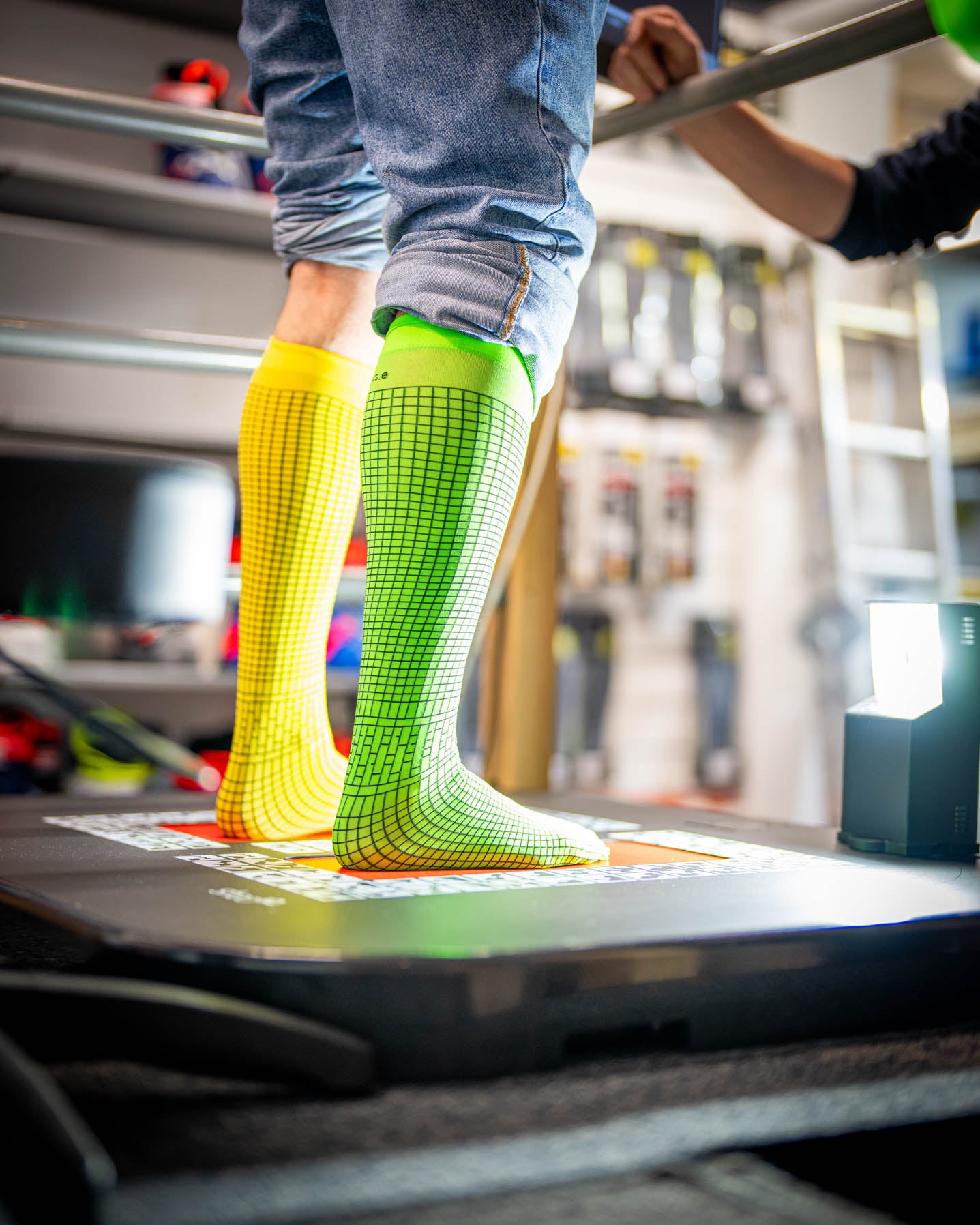 Fußanalyse für Bootfitting bei SF Sports: Zwei Beine stehen auf einer speziellen Plattform, während verschiedene Faktoren wie Fußgröße, Fußgewölbe, Breite und Unterschenkelform gemessen werden. Diese Analyse bildet die Grundlage für maßgeschneiderte Skischuhe, die höchsten Komfort und optimale Leistung bieten.
