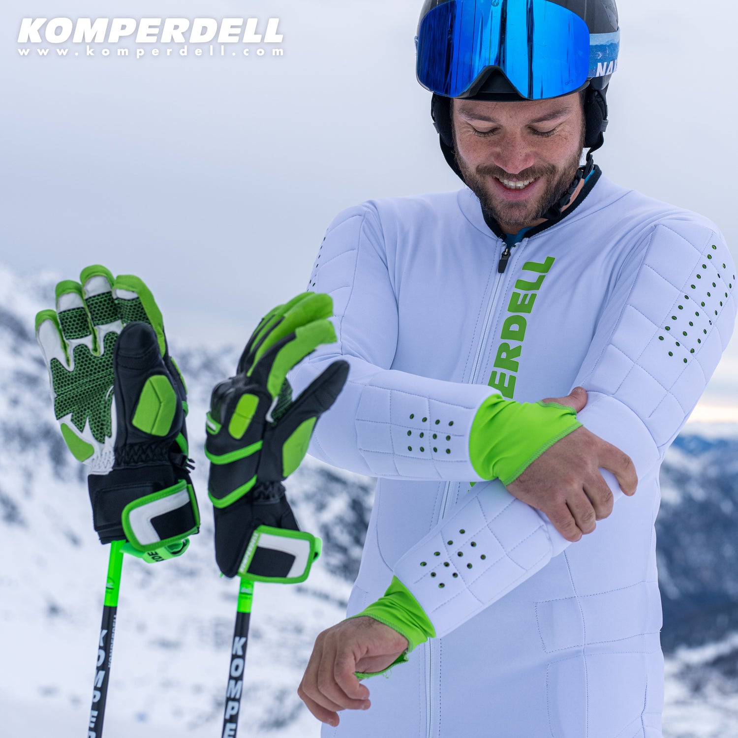 Komperdell Racing Handschuhe in gruener und schwarzer Farbe befestigt an Skistoecken vor verschneiter Bergkulisse, ideal fuer professionellen Skirennsport