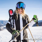 Skifahrerin traegt Komperdell Racing Lobster Handschuhe fuer Erwachsene in schwarz-gruen mit innovativem Protektor und griffiger Handflaeche beim Skifahren auf verschneiter Piste mit Bergpanorama