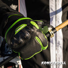 Detailansicht des Komperdell Racing Lobster Handschuhs fuer Erwachsene in schwarz-gruen mit Protektor und rutschfester Handflaeche beim Greifen eines Skistocks