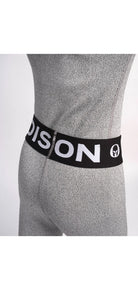 Nahaufnahme einer Person, die Diston Cut Resistant Underpants Junior trägt - hellgraue, strukturierte Sportleggings mit schwarzem Bund und auffälligem weißem "DISTON"-Schriftzug und Logo. Ideal für Skirennläufer. Einfarbig weißer Hintergrund.
