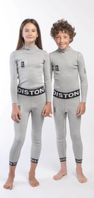 Zwei Kinder stehen nebeneinander in passenden hellgrauen Diston Cut Resistant Unterhosen Junior - 3FIS Stars in CRG (BASE / Performance Fit) mit schwarzem und weißem Diston-Branding am Bund und an den Bündchen vor einem schlichten weißen Hintergrund.