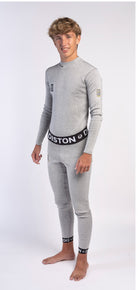 Eine junge Person mit kurzen, lockigen hellbraunen Haaren steht barfuß in hellgrauer Diston DISTON WC Schnittfeste Hosen Herren - 4FIS Stars in CRG - CORE / Racing Fit Unterwäsche, perfekt für den Skirennsport, vor einem weißen Hintergrund.